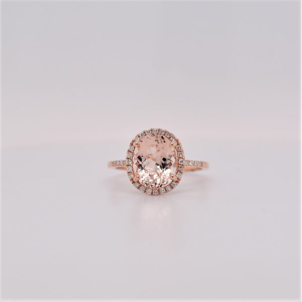 This lovely 14 kt rose gold ring features a 2.60 carat oval morganite gemstone surrounded by a halo of diamonds and the diamo